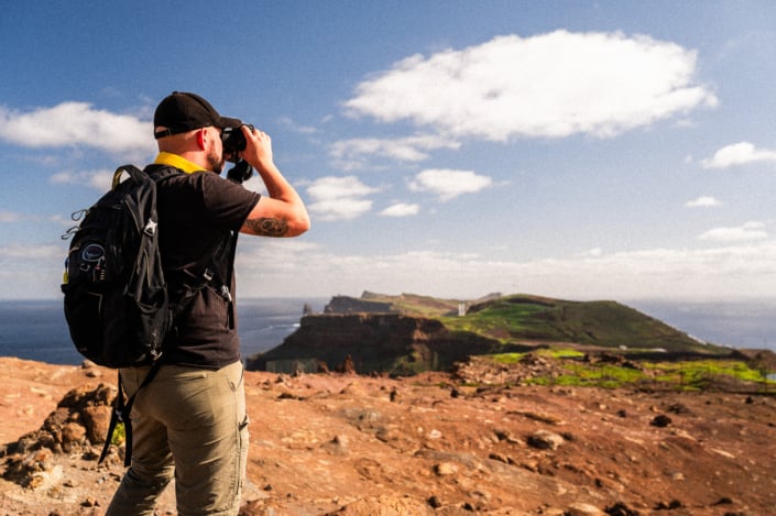 An explorer with binoculars on a rocky island, landscape format