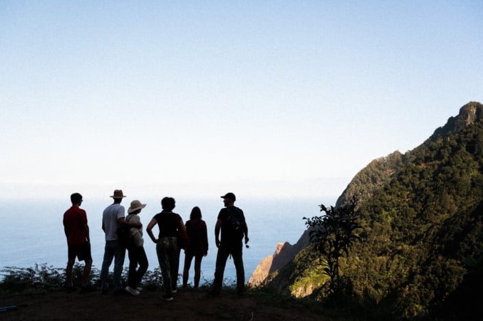 Silhouette of a group of 6 in front of mountain and ocean