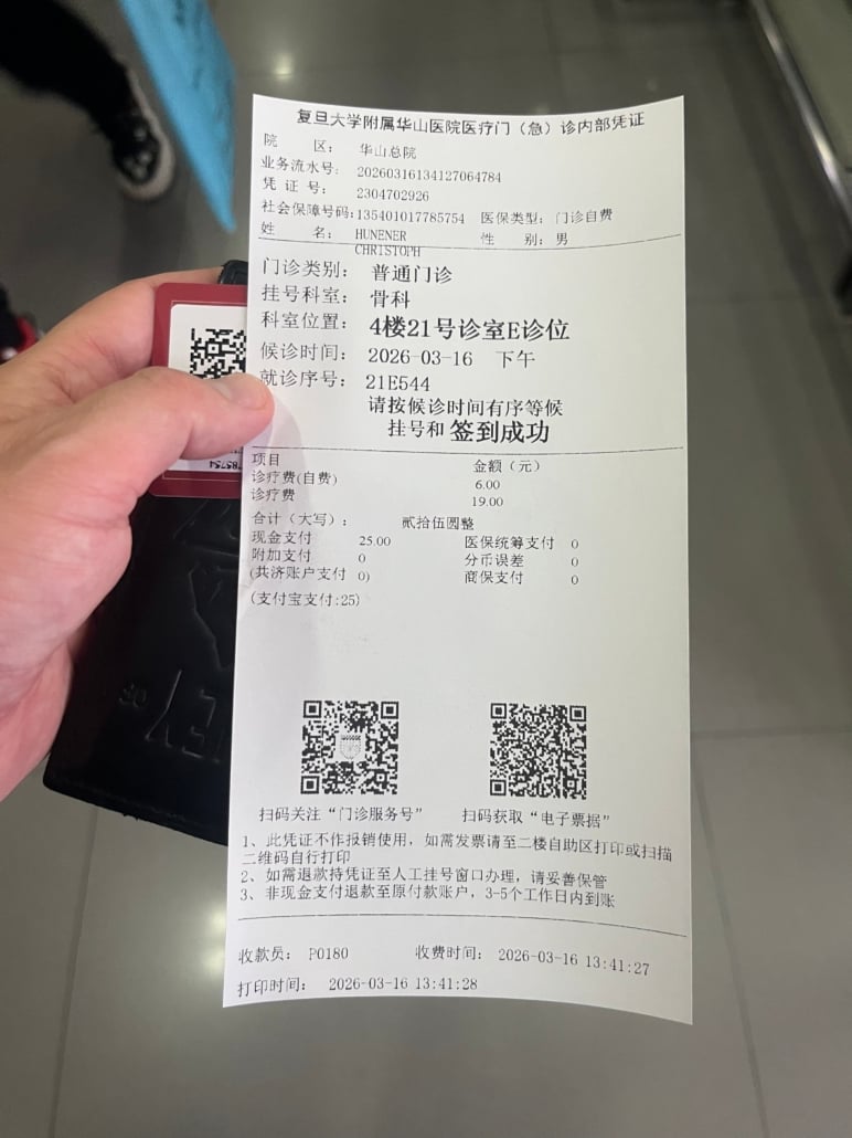 Hand holding a long white medical receipt with Chinese text, detailing department and patient info, and two QR codes at the bottom.