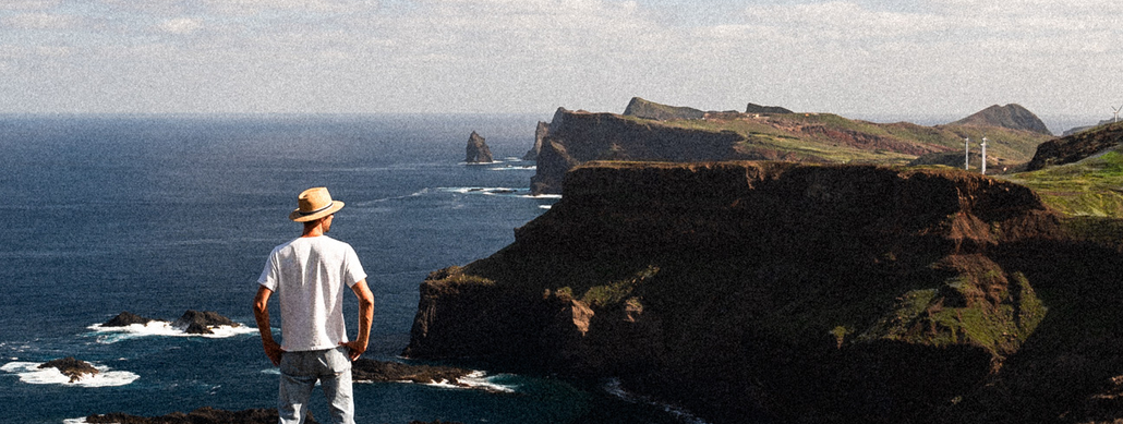 a man standing on a cliff looking at a landscape view 
